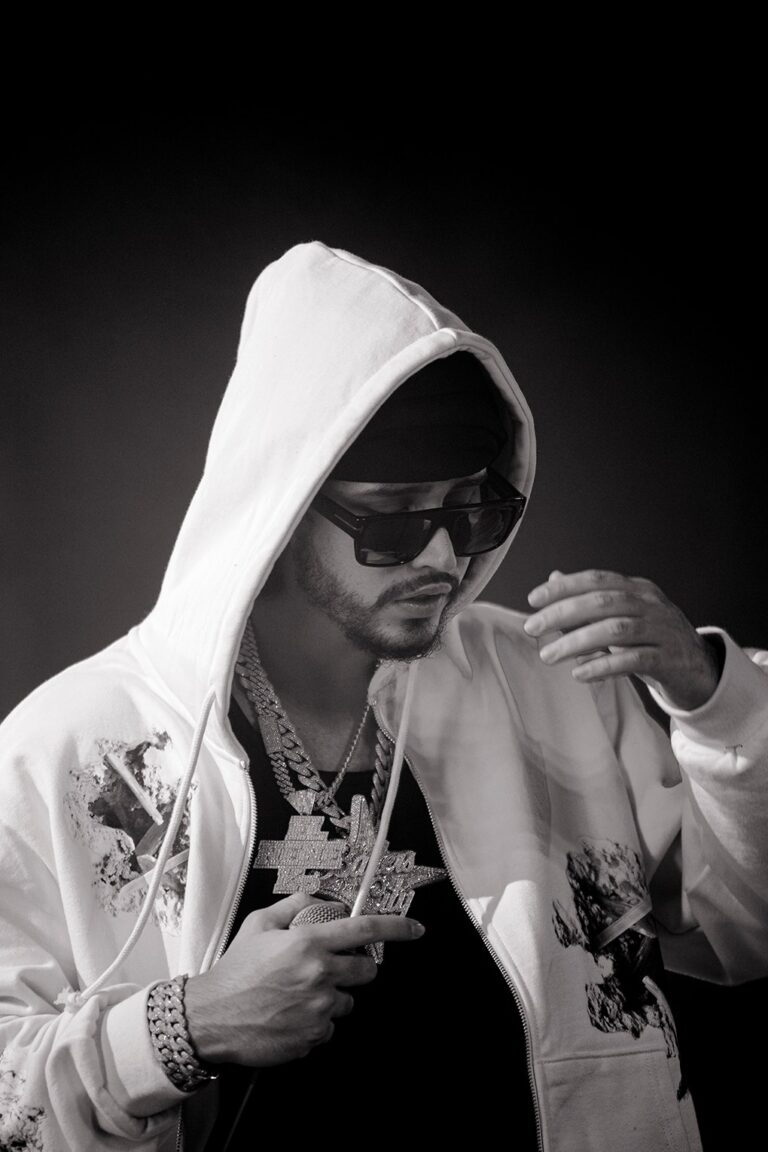 Imagen en blanco y negro de Clarent con su capucha puesta, sus gafas de sol, en donde pueden verse sus joyas al cuello