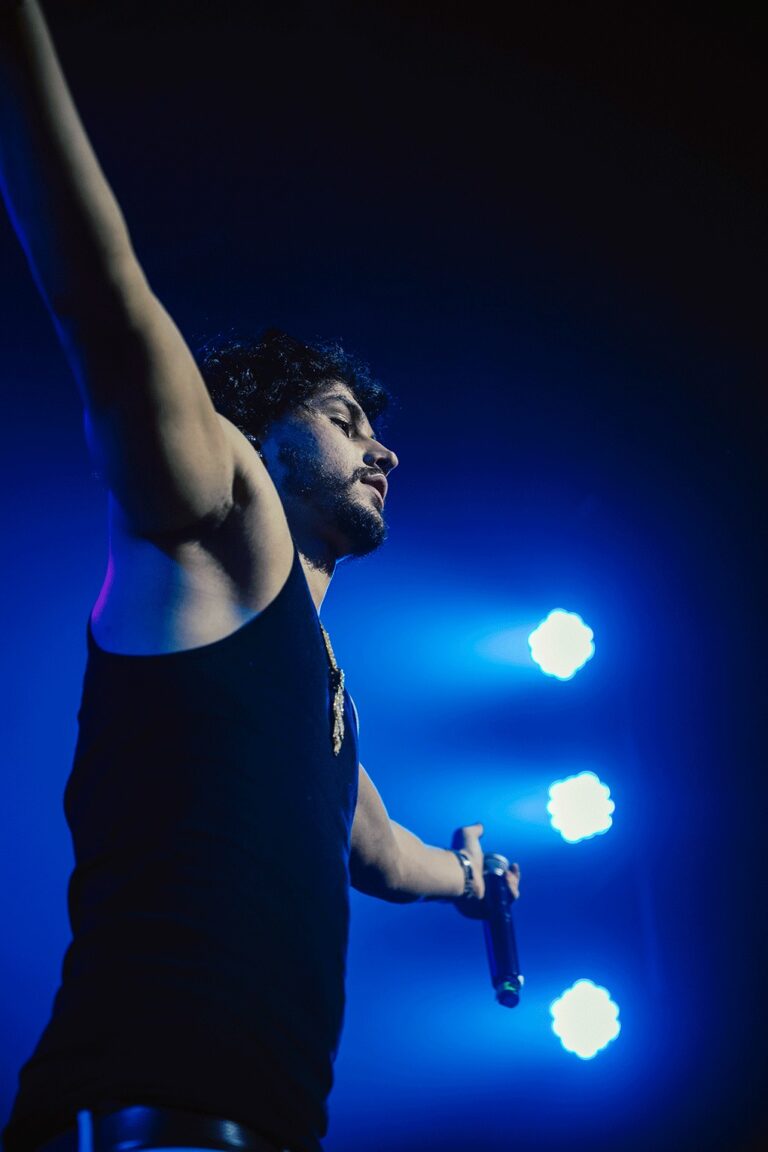 Clarent con los brazos extendidos y en manga corta mirando hacia el público